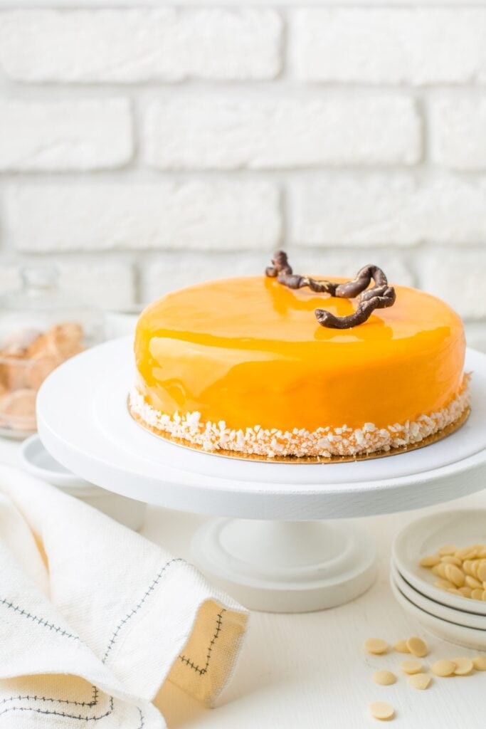 orange glazed cheesecake on a white cake stand
