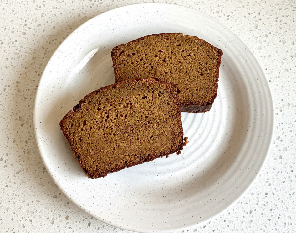 2 slices of apple cider pumpkin bread on a white plate sitting on a white granite countertop