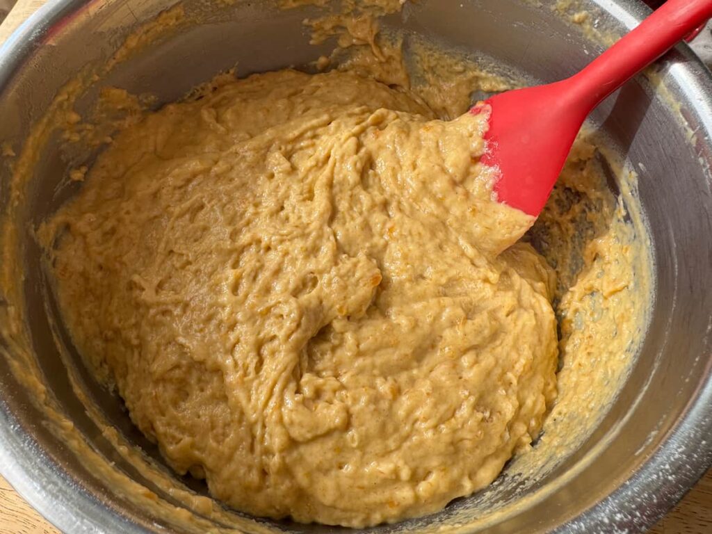peach butter quick bread batter in a stainless steel bowl with a red spatula in the bowl